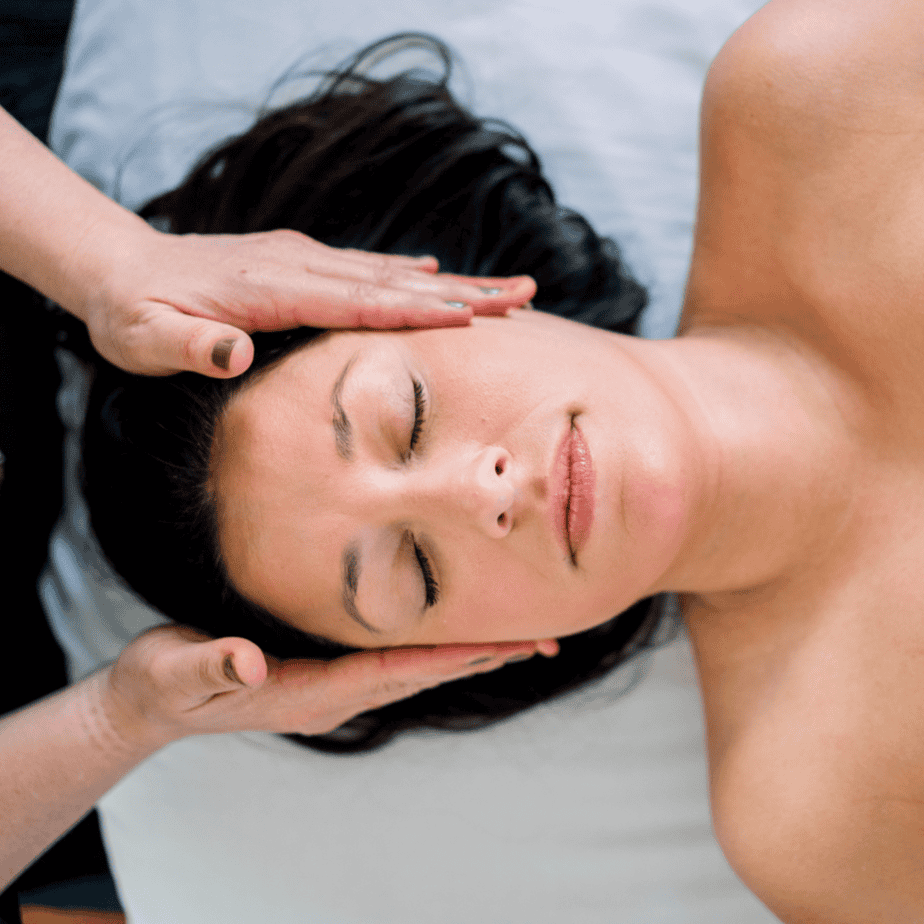 Woman receiving Reiki healing on a massage bed – therapist offering gentle energy support for cancer and chronic illness