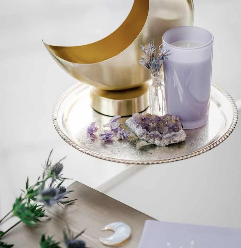 Lilac candle, gold crescent moon, and amethyst crystals on a small altar for holistic healing and spiritual support